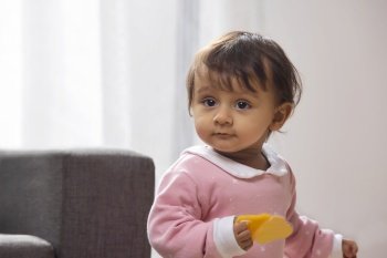 Portrait of a cute baby playing with toy on sofa at home