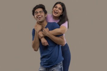 A BROTHER AND SISTER LAUGHING AND POSING TOGETHER IN FRONT OF CAMERA