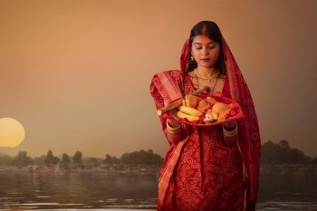 woman from Bihar offers prayers to the  sun  in the  early morning hours   during  Chhath Puja festival
