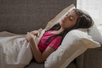 Young girl sleeping peacefully on the couch at home. (Children) 