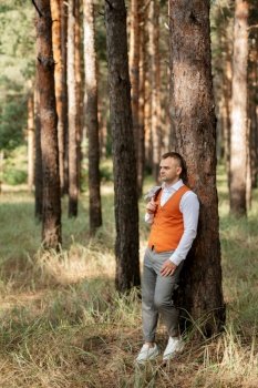 portrait of the groom in a gray suit and an orange vest and white sneakers