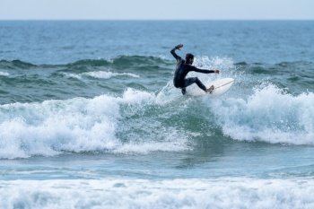 Surfer riding a wave on a cloudy afternoon at Torreira beach, Murtosa - Portugal.