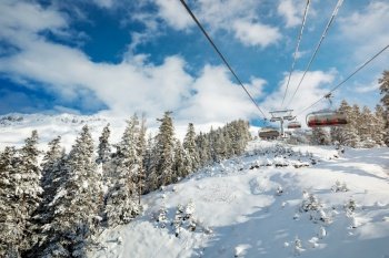 Sunny day at a ski resort. A ropeway over the forest