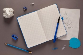 Open notepad and school stationary supplies at paper table background texture. Back to school flat lay concept idea