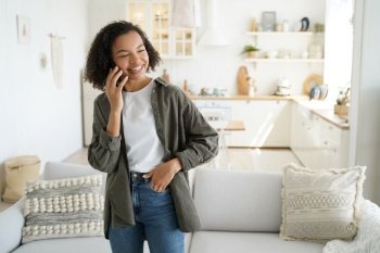 Happy hispanic girl has talk on smartphone at home and laughing. Young african american woman is smiling. Chatting with friends remotely. Schoolgirl has distant discussion with classmates.. Happy hispanic girl has talk on smartphone at home and laughing. Distant discussion.
