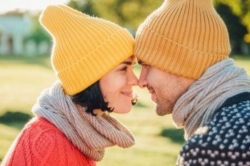 Close up portrait of lovely couple wear warm hats and scarf look with eyes full of happiness and enjoyment, going to have sweet kiss, enjoy togetherness. People, relationship and love concept