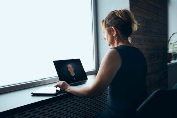 Businesswoman having business video call on laptop in office. Mature busy woman remotely working from office. Female manager using digital devices. Remote communication. Video calling. Remote work