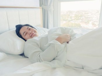 Asian young woman stretching morning wake up in bedroom on bed
