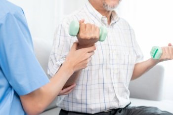 Contented senior patient doing physical therapy with the help of his caregiver. Senior physical therapy, physiotherapy treatment, nursing home for the elderly. Contented senior patient doing physical therapy with the help of his caregiver.