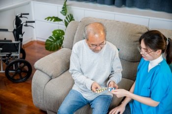 Asian doctor with physician visit senior male patient consult medicine dosage at house in living room, Woman nurse caregiver showing prescription drug to senior man at nursing home, healthcare support