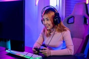 You win. Gamer using joystick controller plays online video game with computer neon lights very determined, woman wear gaming headphones playing live stream esports games console at home