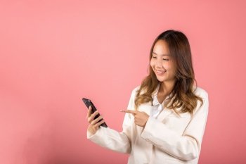 Portrait Asian happy beautiful young woman smile making finger pointing on screen smartphone in hand shopping online application looking to screen, studio shot isolated pink background with copy space