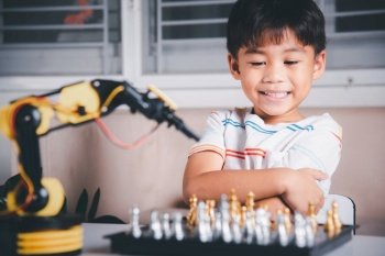 Asian little boy is playing chess with robot machine arm, STEM education E-learning, Funny children learning successful getting a lesson control robot arm, Technology science education concept