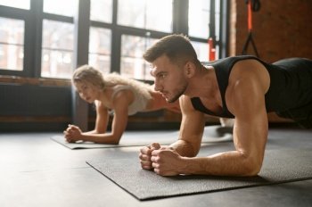 Man and woman stand in plank. Group training at sport club gym class. Focus on sportsman. Fitness workout concept. Man and woman standing in plank training at sport club gym