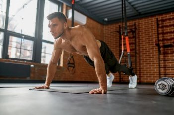Man standing in plank position on arms. Personal training workout at gym sport club without special equipment. Man standing in plank position on arms