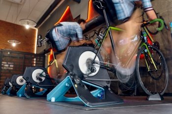 Man exercising cycling gym machine trainer equipment. Bike training. Motion blur shot. Man cycling gym machine equipment, motion blur