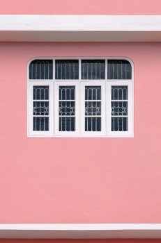 Minimal architecture background of white wooden windows with wrought iron on pink wall of vintage house in vertical frame