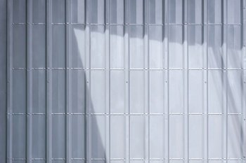 Background of gray sheet metal garage wall with sunlight and shadow on surface