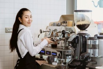 women barista staff worker make a coffee with espresso machine in cafe happy smile looking camera.