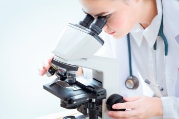 Scientist looking at microscope in science laboratory for virus research in laboratory.