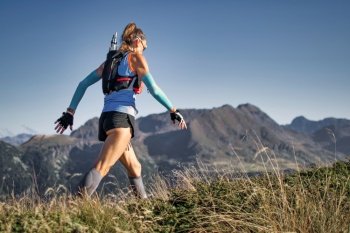 Sporty woman walks during an ultra trail in the mountains of the Italian Alps