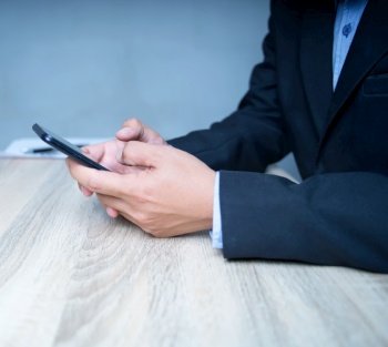 Close-up of a businessman in a suit using a smartphone to communicate with the client View marketing and social networking on the Internet. on the desk at work copy space
