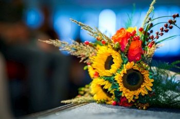 Sunflower wedding bouquet lies on an table of wedding ceremony in church Selective focus. Wedding bouquet made of sunflowers and roses  