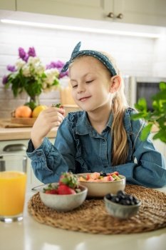 Healthy food at home. Cute little girl eats fruit salad 
