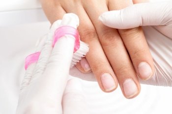 Close-up of manicurist hands is removing dust from nails with a brush to cleaning nails in manicure salon.. Manicure master removes dust.