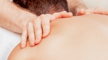 Young man receiving back massage by hands of masseur in spa beauty salon.. Young man receiving back massage.