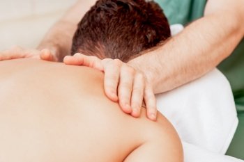 Young man receiving back massage by hands of masseur in spa beauty salon.. Young man receiving back massage.