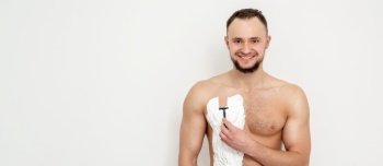 Young caucasian man with beard holds razor shaves his chest with white shaving foam on white background. Man shaving his torso. Young man shaving his chest
