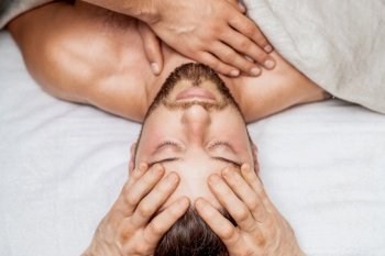 Top view of man receiving relaxing head massage by hands of massage therapist. Man receiving relaxing head massage.