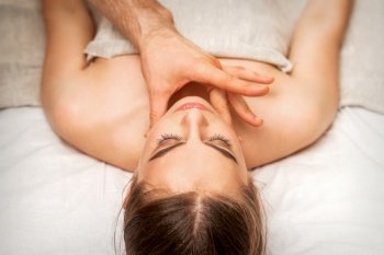Chin or neck massage of a young woman by the hand of a male massage therapist in a spa salon. Chin or neck massage of woman