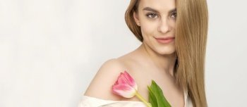 Beautiful caucasian young woman with one tulip against a white background. Young woman with one tulip