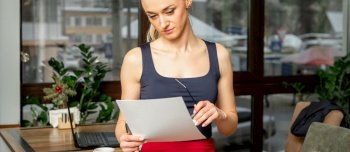 Beautiful young businesswoman looking documents while standing in the office or cafe. Businesswoman looking documents in cafe