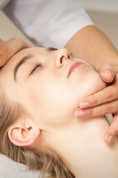 Young caucasian woman receiving a head and chin massage in a spa medical center. Woman receiving head and chin massage