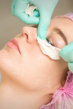 Young woman receiving eyelash removal procedure and removes mascara with a cotton swab and stick in a beauty salon. Young woman receiving eyelash removal procedure and removes mascara with a cotton swab and stick in a beauty salon.