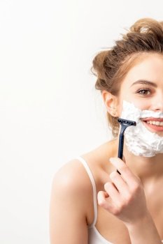 Portrait of beautiful young smiling caucasian woman shaves face with razor on white background. Portrait of beautiful young smiling caucasian woman shaves face with razor on white background.