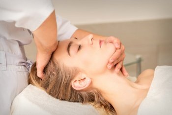Cosmetologist hands doing facial massage on forehead and chin of young female at spa salon. Cosmetologist hands doing facial massage on forehead and chin of young female at spa salon.