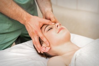 Pretty young caucasian woman receiving a head massage by a male massage therapist in a beauty salon. Pretty young caucasian woman receiving a head massage by a male massage therapist in a beauty salon.