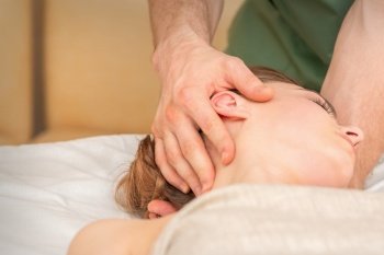 Osteopath doing massage on the female head in rehabilitation clinic center. Osteopath doing massage on the female head in rehabilitation clinic center.