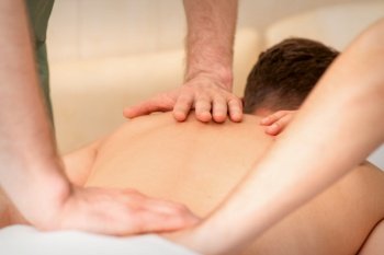 Young man receiving back massage in four hands in spa beauty salon. Young man receiving back massage in four hands in spa beauty salon.