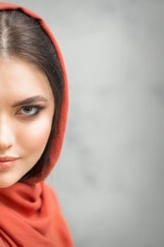 Portrait of a pretty young caucasian woman with makeup in a red headscarf on gray background. Portrait of a pretty young caucasian woman with makeup in a red headscarf on gray background.