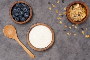 Healthy lifestyle concept, Greek yogurt fresh blueberry and granola in wood bowl on grey background.