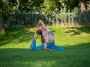 Young yogi woman stretching legs in park. Yoga time. Green grass, park, summer morning. Relaxing and meditating, Health concept. High quality photo. Young yogi woman stretching legs in park. Yoga time. Green grass, park, summer morning. Relaxing and meditating, Health concept.