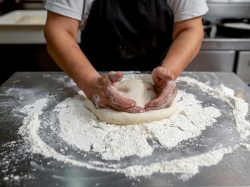 Woman making pizza dough on stainless steel counter