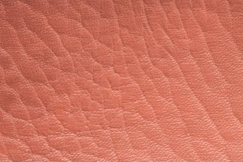Coral color artificial or synthetic leather background with neat texture and copy space, pink fabric sample with leather-like finish aimed for upholstery, fashion, sewing or footwear projects