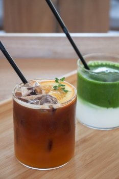 Iced americano with orange and iced matcha green tea in coffee shop, stock photo