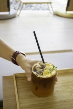 Iced black orange coffee on wooden table, stock photo